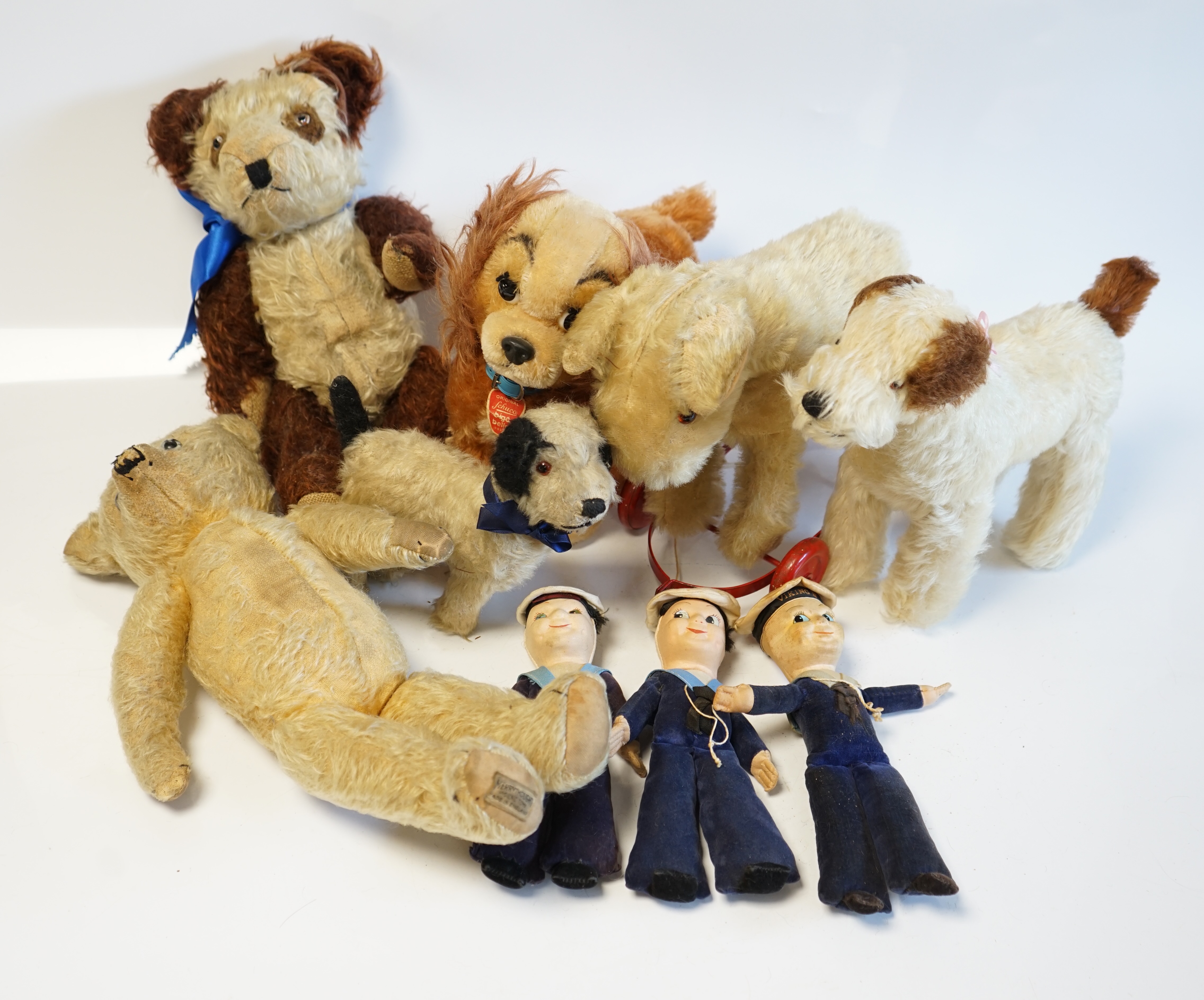 A Schuco Bigo Bello dog 'Lady', with collar and label, three Norah Wellings sailor dolls, four other toys, a 1930's Merrythought Teddy, with button and label, some hair loss, and a Merrythought dog on wheels (10). Condit